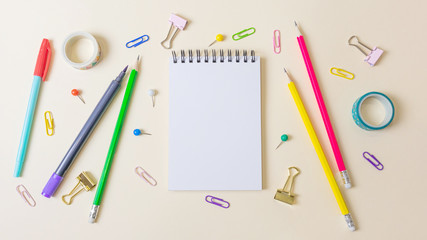 Pens, paper clips, notebook and other stationery on a light pastel background. Banner. Place for text, minimalism. School, office, education concept.