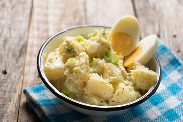 Potato salad with egg and mayonnaise on wooden background