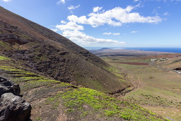 Panoramic view at landscape in the south of canary island Lanzarote with lava rocks and mountain in the foreground and the atlantic ocean in the background.