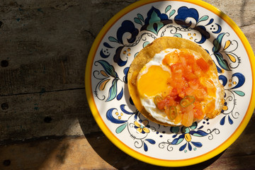 Mexican egg mounted on corn tortilla with sauce also called 