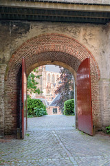 Fototapeta na wymiar Cathedral in the city of Leiden, The Netherlands, seen through large medieval gate with red doors