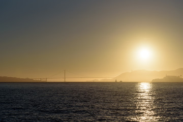Sunset over Alcatraz island in San Francisco bay area, with Golden Gate bridge in background