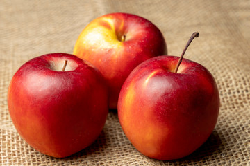 Apples. Three red ripe apples on burlap.