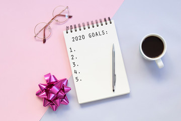 Top view of a flat lay of desktop and notepads for writing down goals and plans. 2020 New Year's goal, plan, action text on notepad with office accessories. Business motivation, inspiration concept.