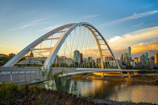 Fototapeta Edmonton, Alberta, Canada skyline at dusk with suspension bridge in foreground and clouds