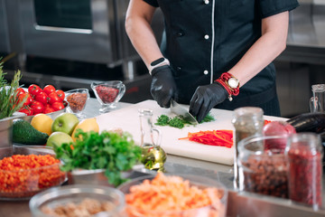 A Woman Chef cuts vegetables in the kitchen in a restaurant.