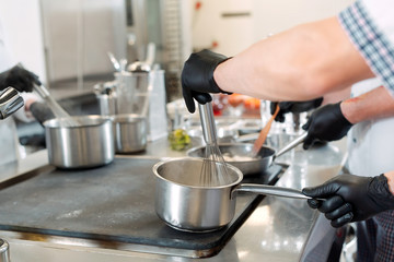 Cooks prepare meals on an electric stove in a professional kitchen in a restaurant or hotel.