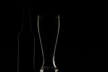 Empty dark bottle and glass on a dark background