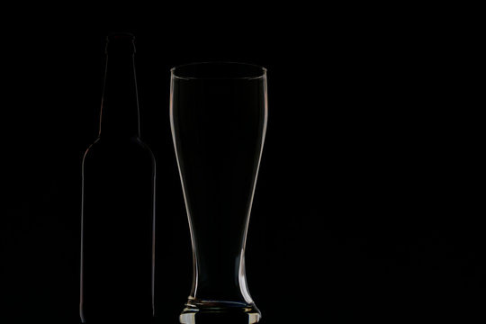 Empty dark bottle and glass on a dark background