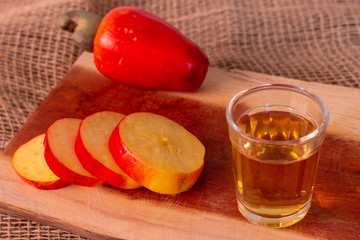 A shot of cachaca with a fresh cashew slices. best way to drink cachaca. 