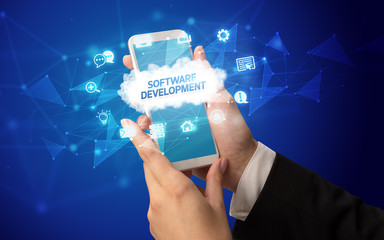 Female hand holding smartphone with SOFTWARE DEVELOPMENT inscription, cloud technology concept