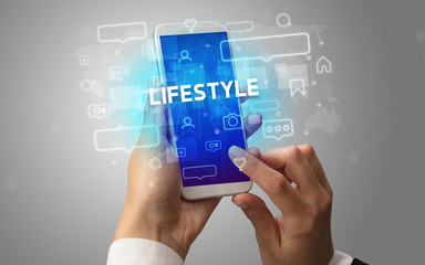 Female hand typing on smartphone with LIFESTYLE inscription, social media concept