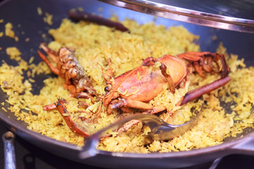 Delicious Homemade Seafood Lobster Paella studded with succulent lobsters, a renown Spanish dish with its characteristic golden colored rice flavored with saffron. Mediterranean, Traditional Cuisine.