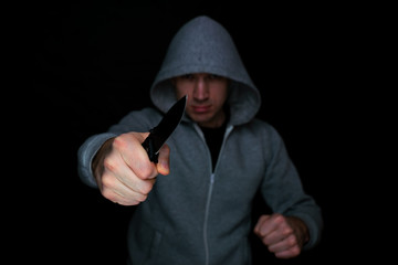 A man with a knife in his hand comes out of the dark. Selective focus