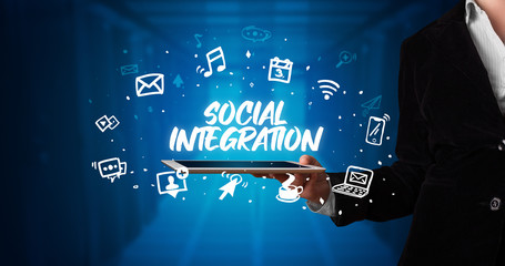 Young business person working on tablet and shows the inscription: SOCIAL INTEGRATION