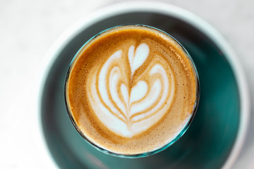 Cup of cappuccino with coffee art on a table in a cafe, top view