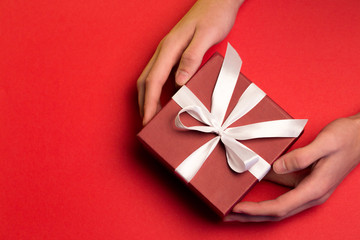 Top view of male hands holding red present box on red background, Valentine's gift concept, top view