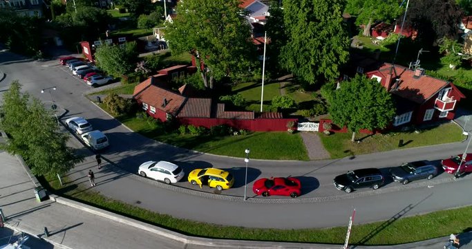 Aerial view and a pull back revealing the small boat harbor including a Ferrari in Sigtuna a summer afternoon