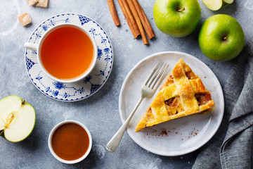 Apple pie on a white plate and cup of tea. Grey background. Top view.