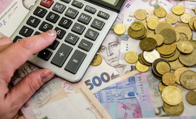 hand calculates income using a calculator. Ukrainian hryvnia. Much money. 500 hryvnias on the table