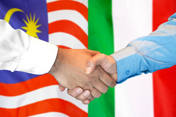 Business handshake on the background of two flags. Men handshake on the background of the Malaysia and Italy flag. Support concept