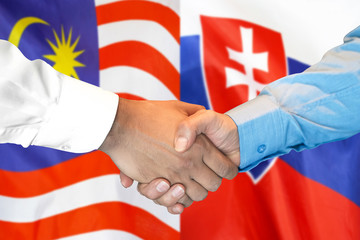 Business handshake on the background of two flags. Men handshake on the background of the Malaysia and Slovakia flag. Support concept