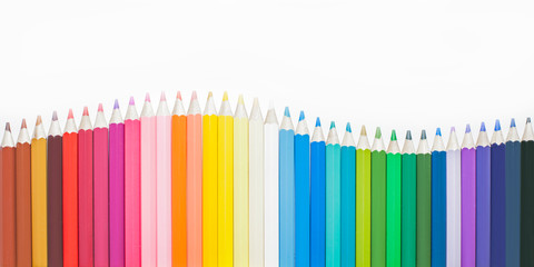 Beautiful multi-colored pencils lined up in a row, blurred background.