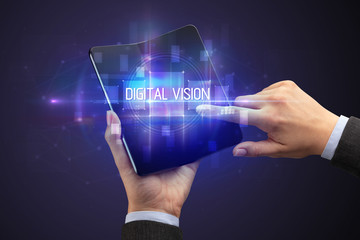 Businessman holding a foldable smartphone with DIGITAL VISION inscription, new technology concept