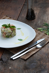 Tartar salmon with herbs on white dish