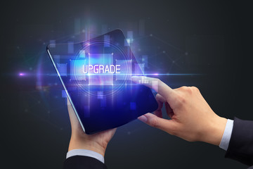 Businessman holding a foldable smartphone with UPGRADE inscription, new technology concept