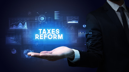 Hand of Businessman holding TAXES REFORM inscription, business success concept