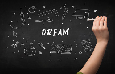 Hand drawing DREAM inscription with white chalk on blackboard, education concept
