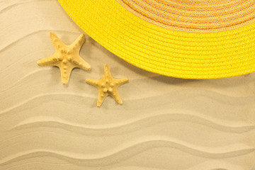 Fototapeta na wymiar Starfish and yellow hat on the beach summer time