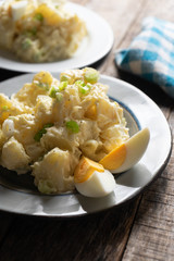 Potato salad with egg and mayonnaise on wooden background