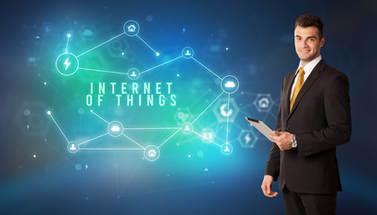 Businessman in front of cloud service icons with INTERNET OF THINGS inscription, modern technology concept