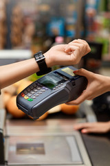 Young adult woman paying for shopping using smart watch
