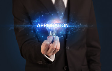 Businessman holding light bulb with APPLICATION inscription, innovative technology concept