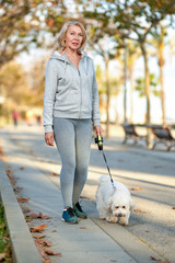 Elderly woman walking with a dog outdoors.