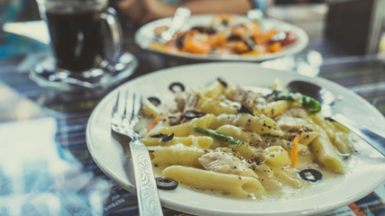 Yummy pasta on cafe table. Closeup plate with portion of tasty pasta with cream sauce placed on table in restaurant