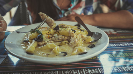 Yummy pasta on cafe table. Closeup plate with portion of tasty pasta with cream sauce placed on...