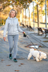 Elderly woman walking with a dog outdoors.
