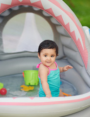 Little baby girl play in swimming pool