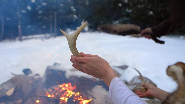 Closeup selective focus footage on hands of a native tribesman and shaman priest, holding antlers and eagle feathers during mystical ritual by fire