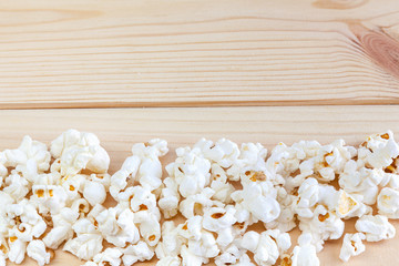 Heap of delicious popcorn, on wooden background . Scattered popcorn texture background.