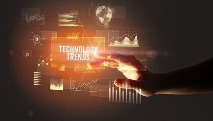Hand touching TECHNOLOGY TRENDS inscription, new business technology concept