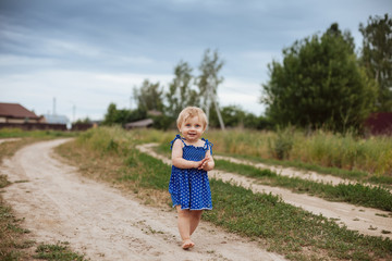 Naklejka na ściany i meble Toddler girl barefoot on village road.