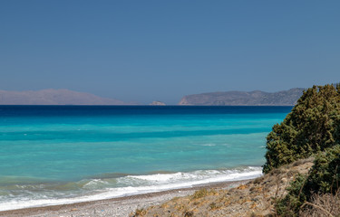 Gravel / pebble beach at the southwest coast of Rhodes island near Apolakkia with multi colored ocean water
