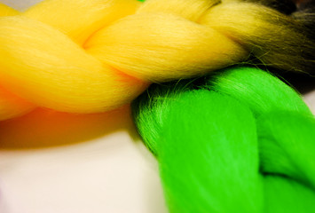 Kanekalon . Colored artificial hair strands. Synthetic hair materials for weaving African braids zizi. Close-up of bright colored hair. Overhead locks. Background for business cards. Yellow, green.
