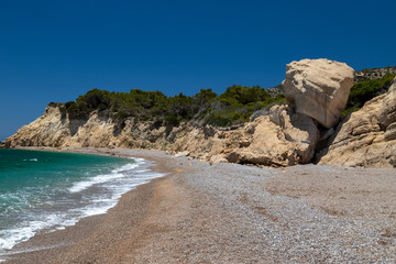 Gravel / pebble beach Akra Fourni nearby Monolithos  at Rhodes island with multi colored ocean water and rock formation