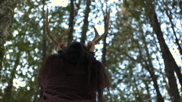 A Native American man is seen from behind with antlers, worshipping Awi Usdi, the Cherokee Little Deer God, animal kingdom respect and responsibility
